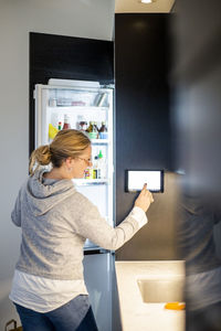 Woman using digital tablet on smart refrigerator at modern home