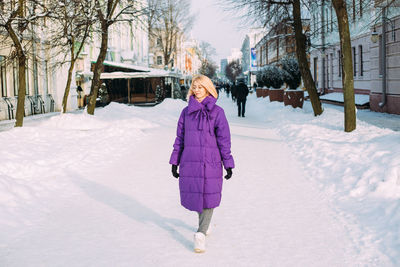 Young stylish blonde with glasses on the street in the snow.