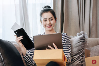 Young woman using digital tablet while sitting on sofa at home