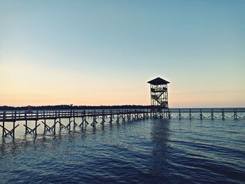 Pier over sea against clear sky during sunset