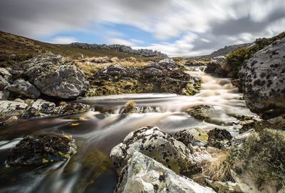 River flowing through rocks against sky