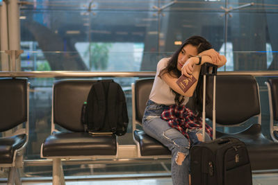 Woman with luggage sitting at airport departure area