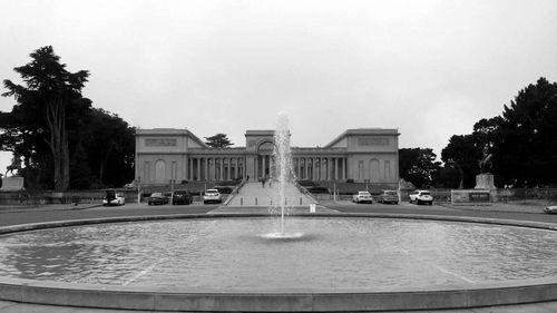 Fountain in front of historic building against sky