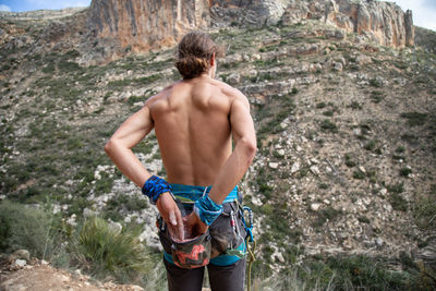 Rear view of shirtless man standing on rock