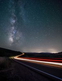Light trails on road against star field at night
