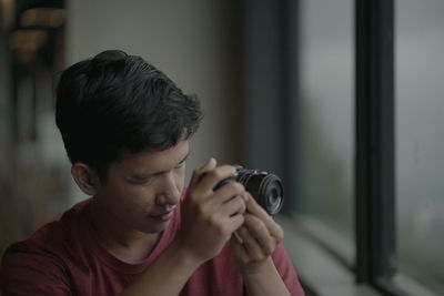 Young man photographing through window