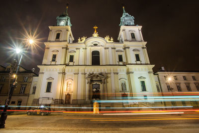 Light trails on road against buildings at night