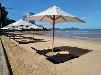 Deck chairs on beach against sky