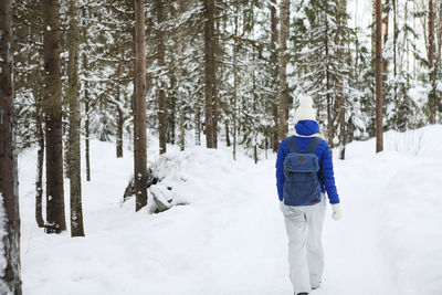 Rear view of man walking on snow covered land