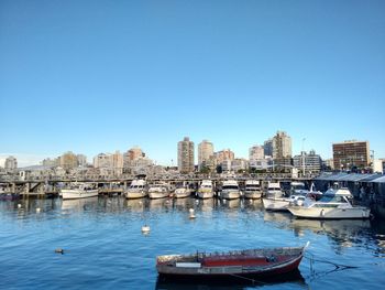 Boats in harbor against clear sky