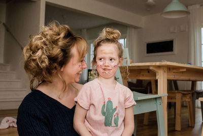 Mother and daughter pulling silly faces whilst playing dress up