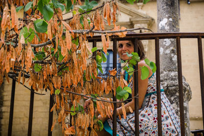 Portrait of young woman standing by railing