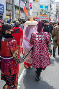 Rear view of people walking on street in city