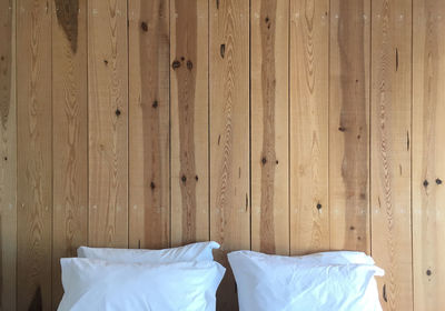 Close-up of white pillows against wooden wall