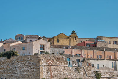 Buildings in city against clear blue sky