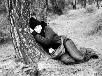 Full length of woman leaning on tree trunk during winter