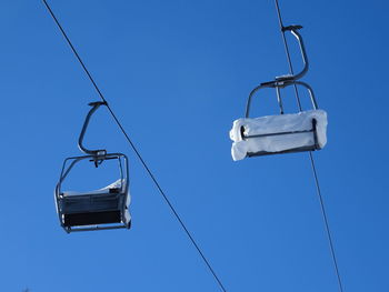 Low angle view of ski lift against blue sky