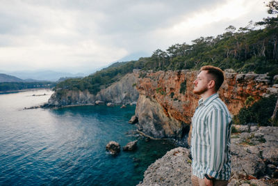 Man looking at waterfall against sky