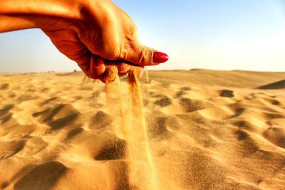 Close-up of hands on sand at beach