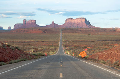 Empty road leading towards rock formations at monument valley