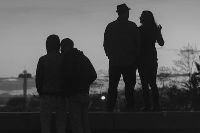 Rear view of couple standing against sky during sunset