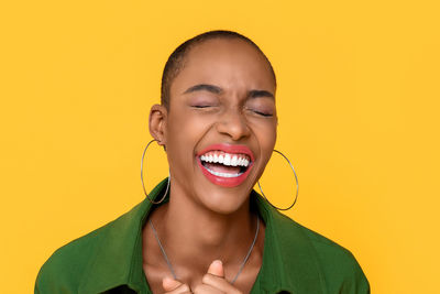 Close-up of smiling woman standing against yellow background