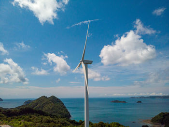 Wind turbine by sea against sky