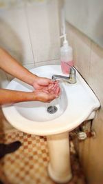 Cropped hands of person washing hands in sink