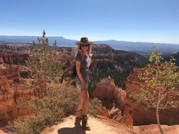 Full length of young woman standing on mountain against sky