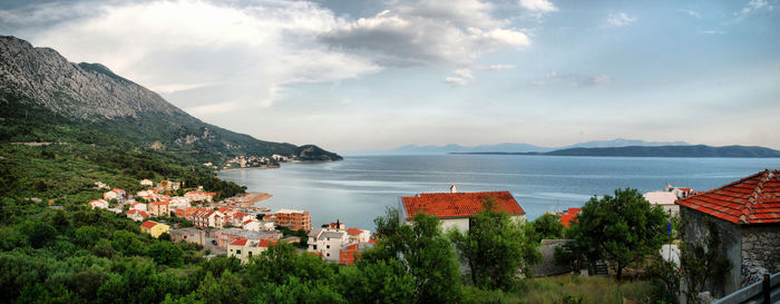 Scenic view of town by sea against sky