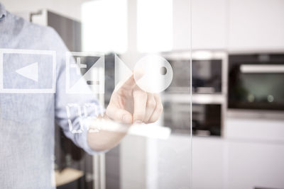 Man's hand using touchscreen of oven in his kitchen