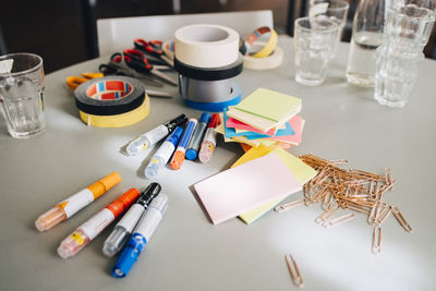 High angle view of stationery with drinking glasses on table at office