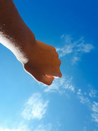 Low angle view of hand against blue sky