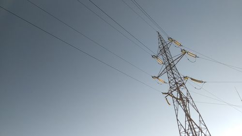 Low angle view of electricity pylon against clear sky