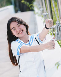 Portrait of smiling young woman hanging on railing