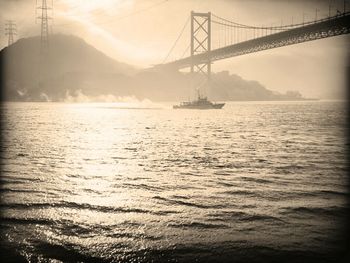 Suspension bridge over sea during sunset