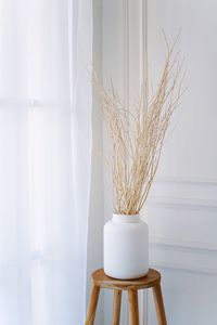 Close-up of vase on table against wall at home