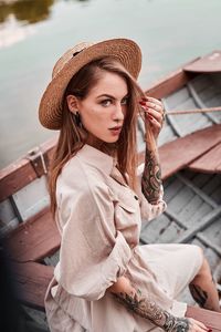 Portrait of young woman wearing hat while sitting in boat