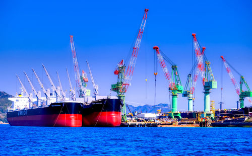 Boats at harbor against blue sky