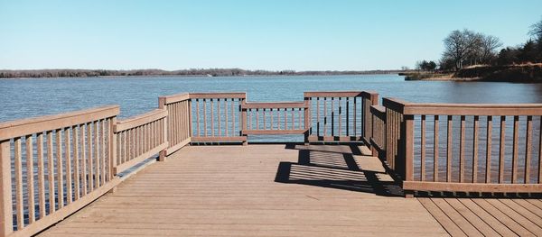 Pier over lake against clear blue sky