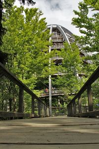 Footbridge over trees against sky