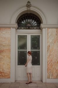 Woman standing against door of window