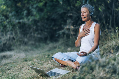 Young man using mobile phone while sitting on land