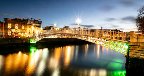 Illuminated bridge over river at night