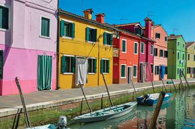 Colorful buildings and boats in front of a canal at burano, a little town full of canals in italy.