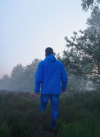 Rear view of man standing on field against sky