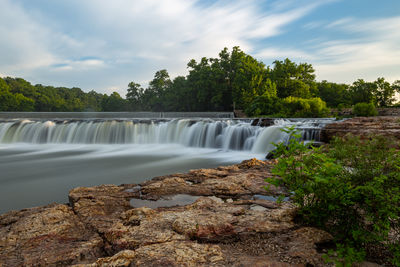 Scenic view of waterfall against sky