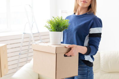 Midsection of woman carrying boxes at home