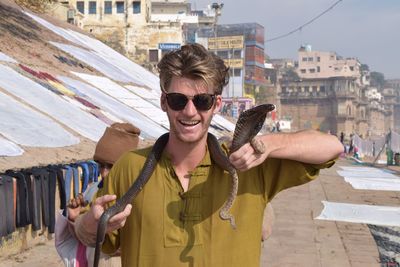 Tourist holding cobra against buildings in city