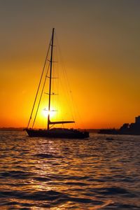 Sailboat sailing in sea at sunset